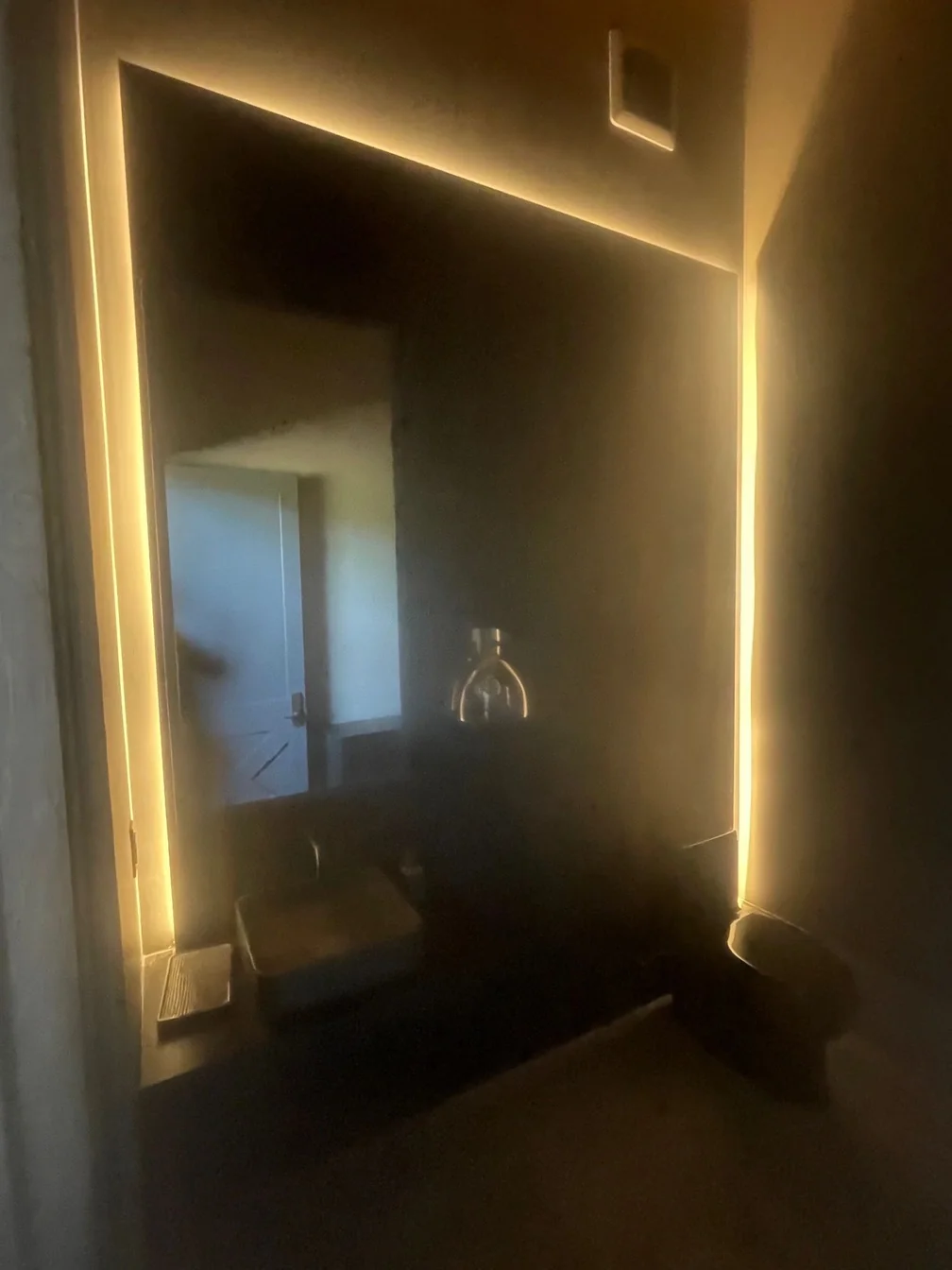 A hallway lit only by a warm strip of cove lighting running up the wall.