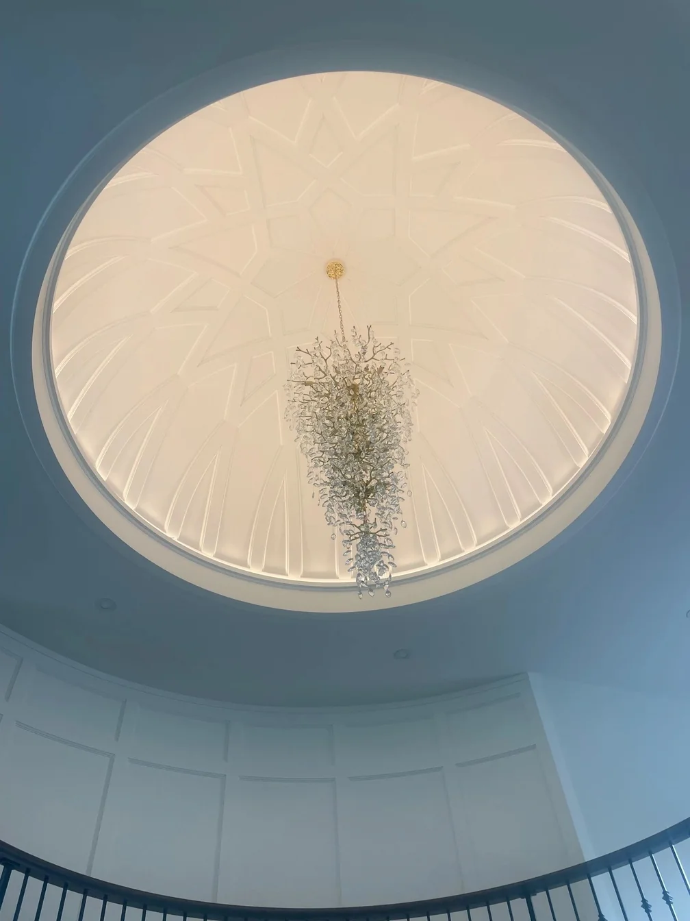 Looking up into a domed ceiling with a starburst chandelier at its centre.