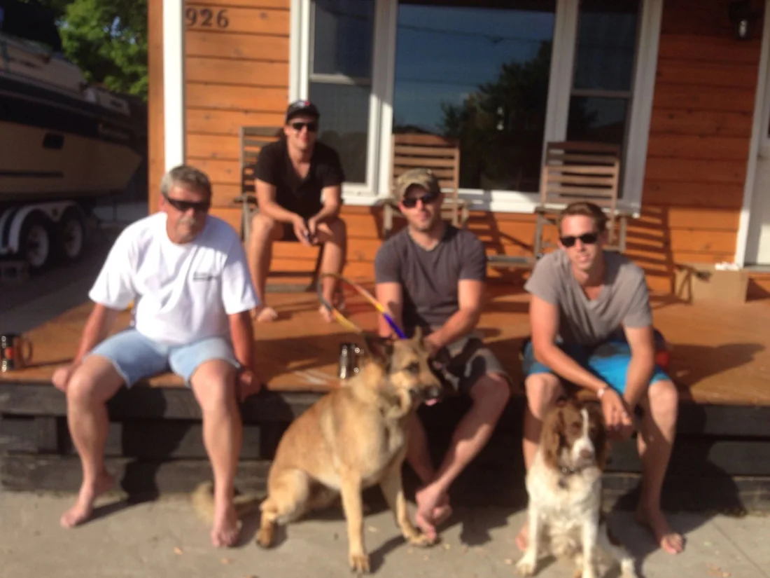 The crew on the front steps of a house with two dogs.