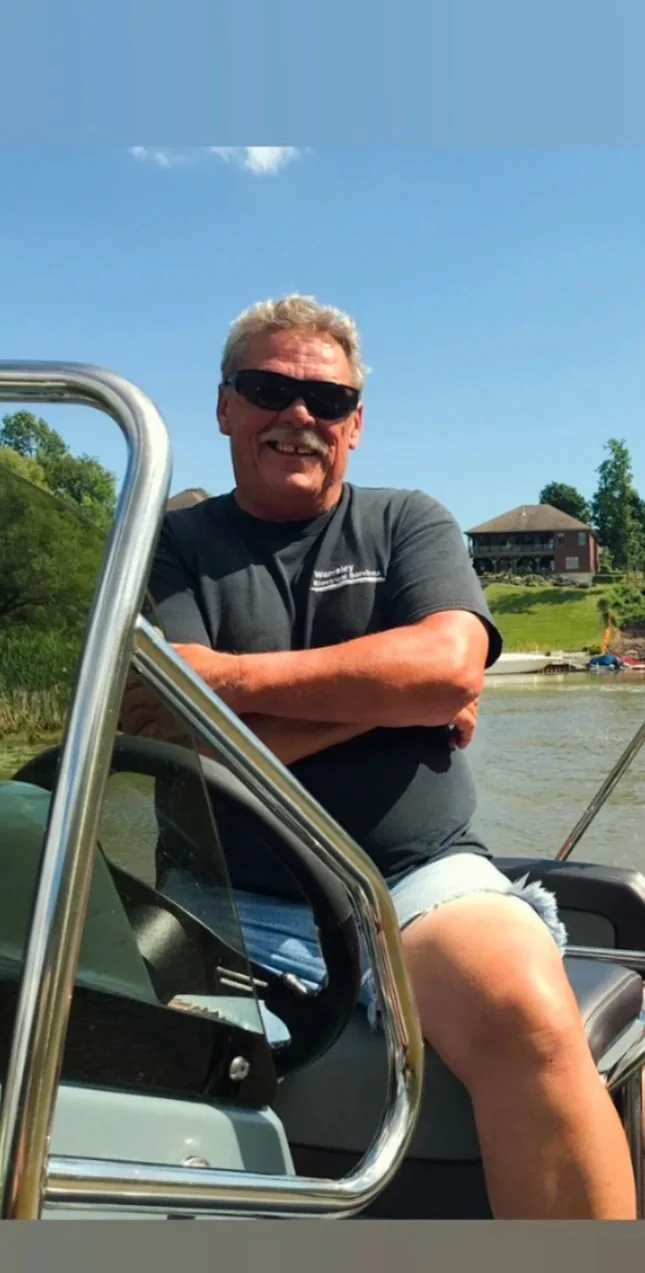 A man in sunglasses leaning on the rail of a boat.
