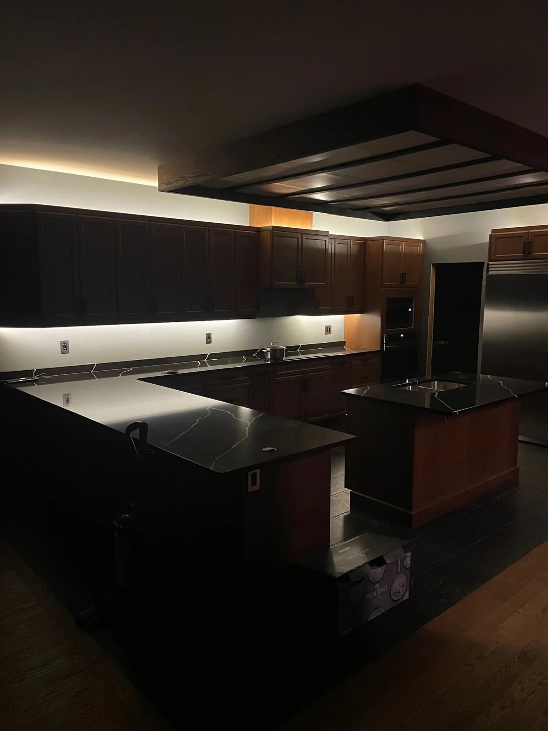 A dark modern kitchen with under cabinet lighting and black cabinetry.